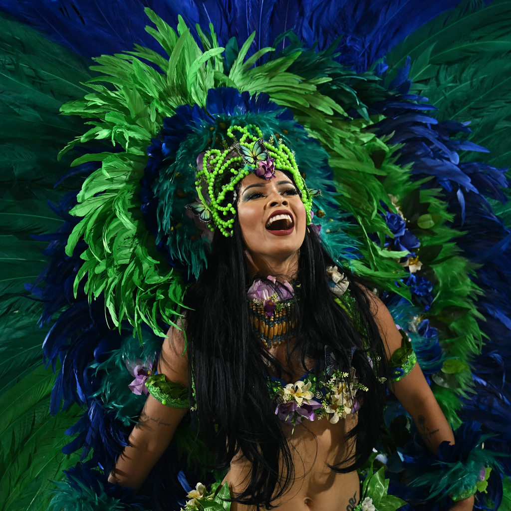 A woman in a blue and green carnival costume in the middle of a samba dance