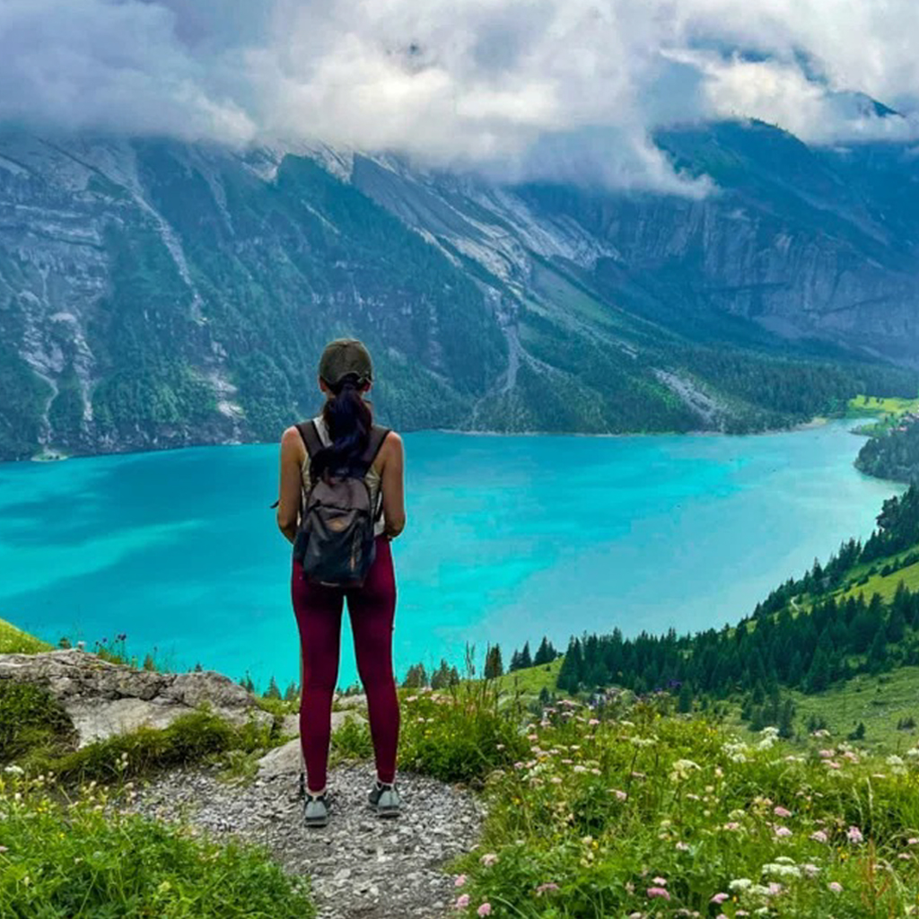 A woman with a backpack looking at the Unesco-listed lake in Switzerland surrounded by mountains.